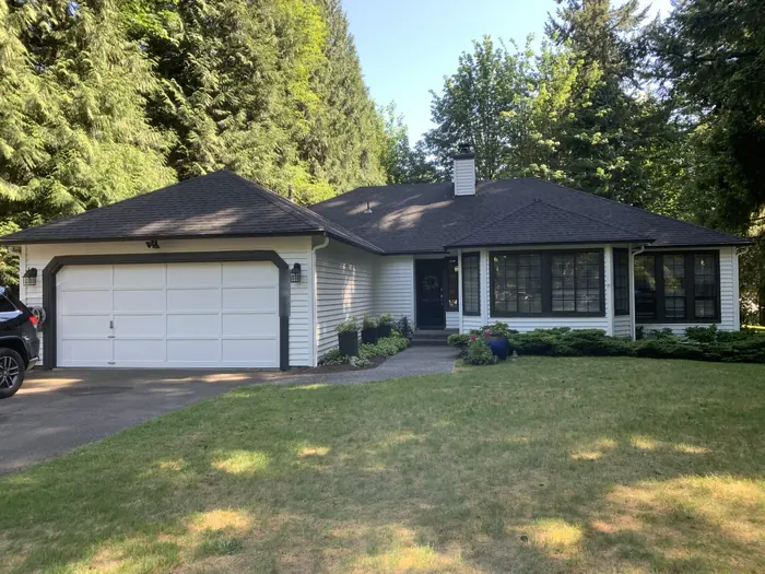 Single-story rambler after: bright white siding with black trim and black window frames