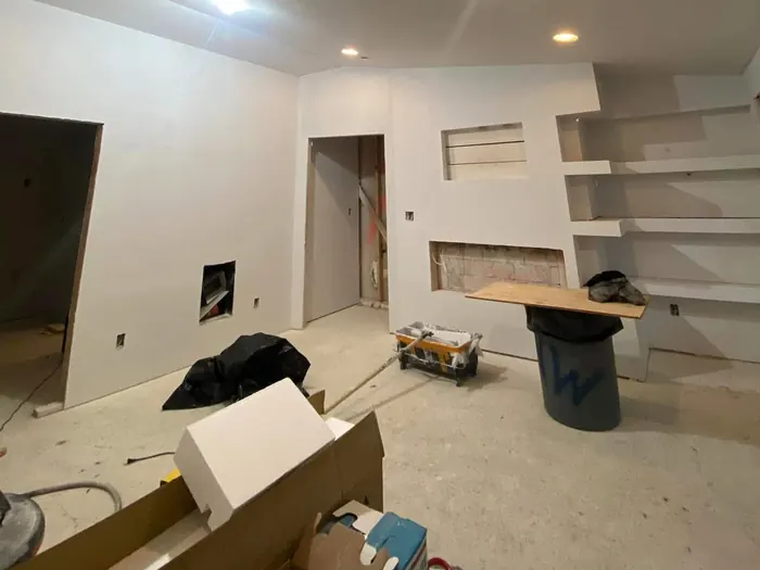 Room mid-construction with bare drywall and unfinished built-in shelves