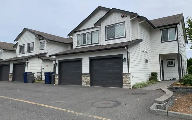 Multi-unit townhome building with white siding and dark trim