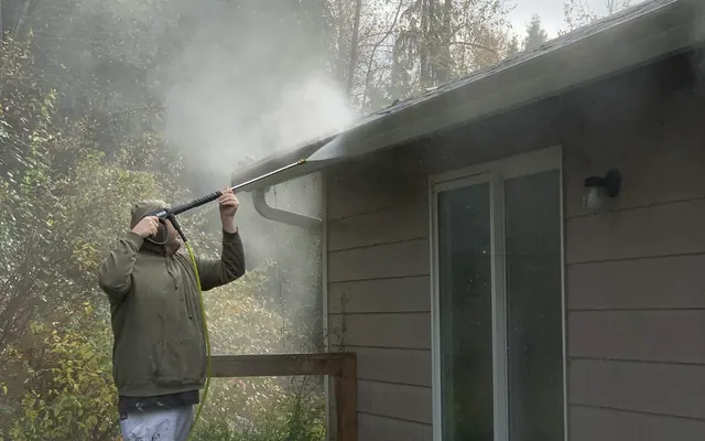 North Line painter pressure washing a roofline and gutter