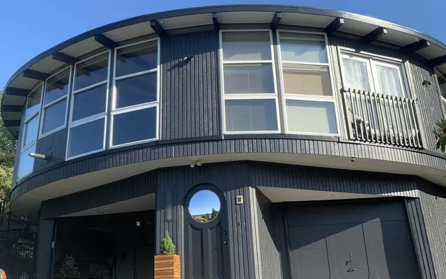 Round mid-century home repainted in deep charcoal with white window trim