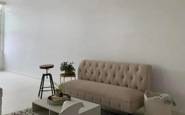 Freshly painted white living room wall with a tufted sofa