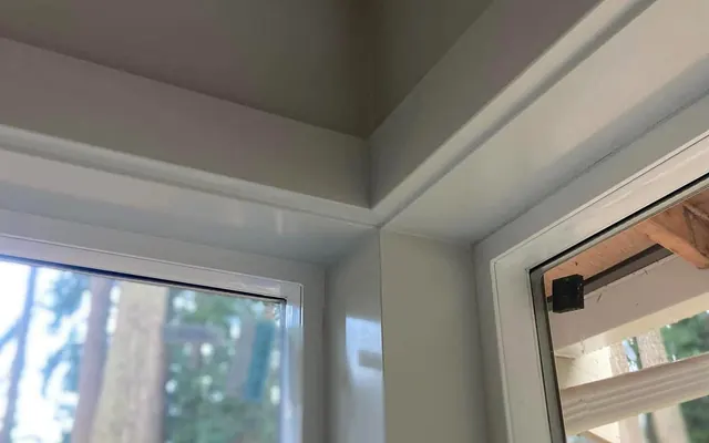 Close-up of a smooth, glossy painted window casing and trim joint
